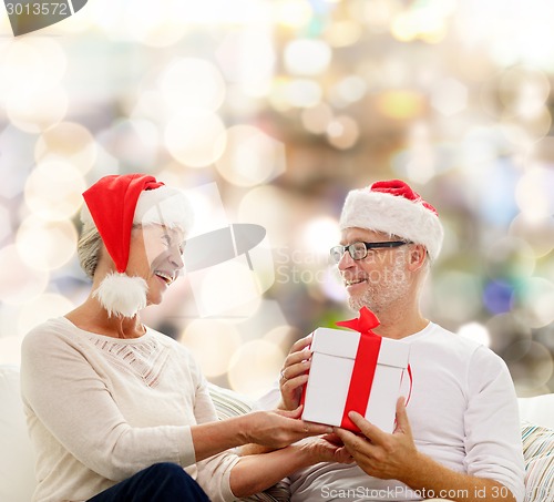 Image of happy senior couple with gift box at home