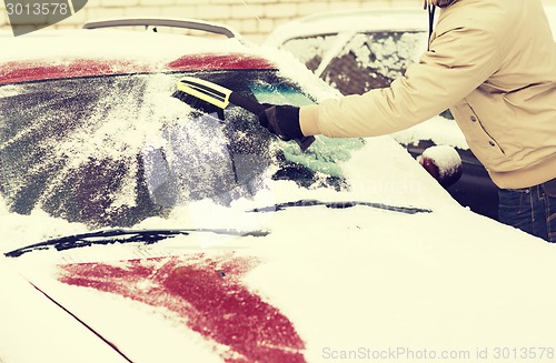 Image of closeup of man cleaning snow from car