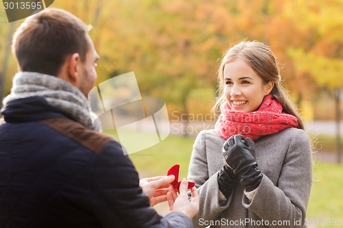 Image of smiling couple with engagement ring in gift box