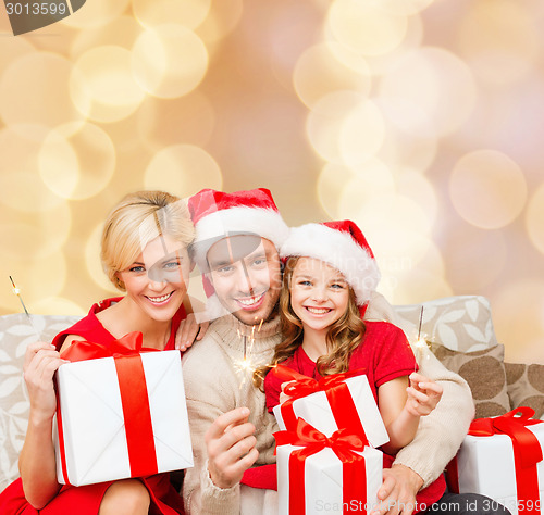 Image of happy family in santa helper hats with gift boxes