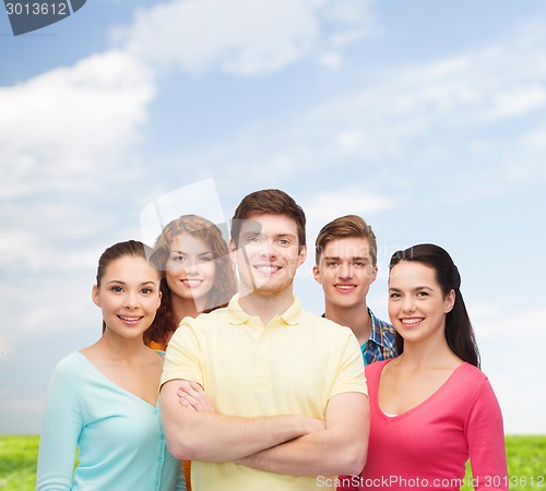 Image of group of smiling teenagers over blue sky and grass