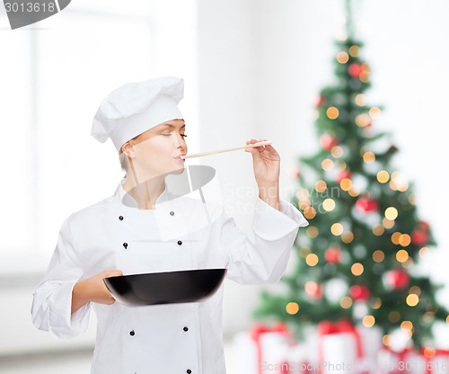 Image of smiling female chef with pan and spoon