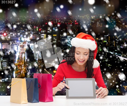 Image of smiling woman with shopping bags and tablet pc