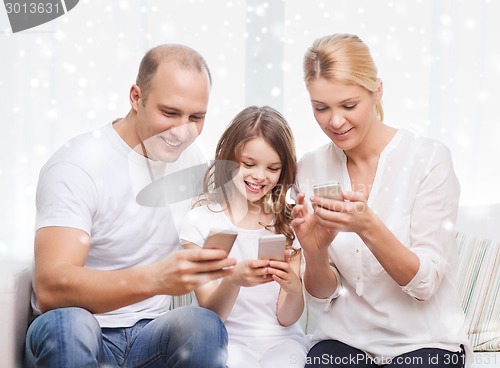 Image of happy family with smartphones at home
