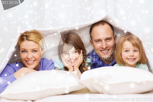 Image of happy family with two kids under blanket at home