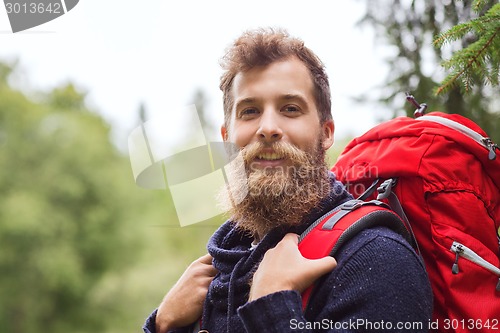Image of smiling man with beard and backpack hiking