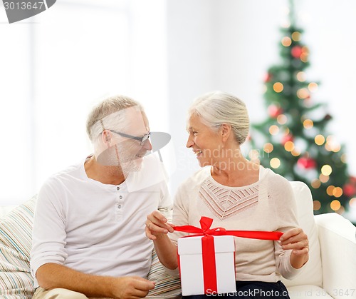 Image of happy senior couple with gift box at home