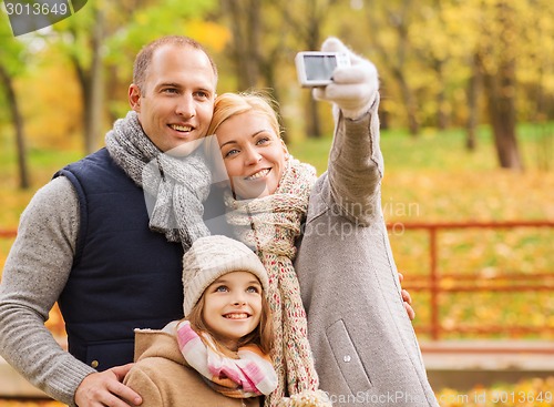 Image of happy family with camera in autumn park