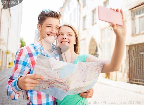Image of smiling couple with smartphone in city