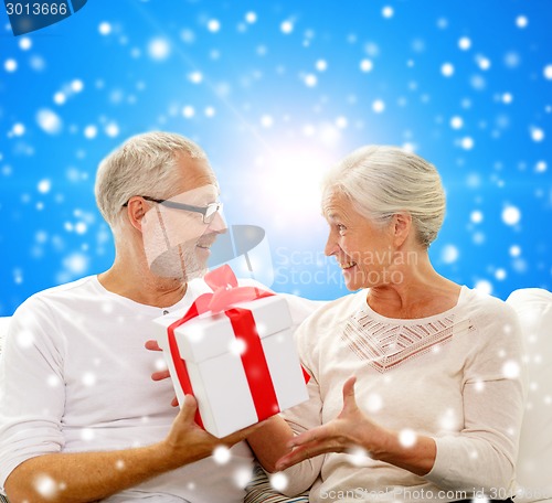 Image of happy senior couple with gift box at home