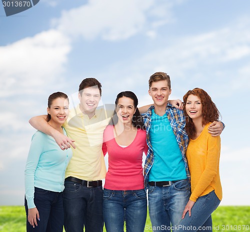 Image of group of smiling teenagers over blue sky and grass