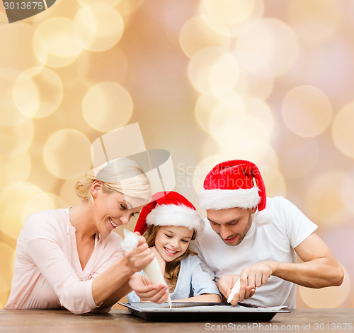 Image of happy family in santa helper hats cooking