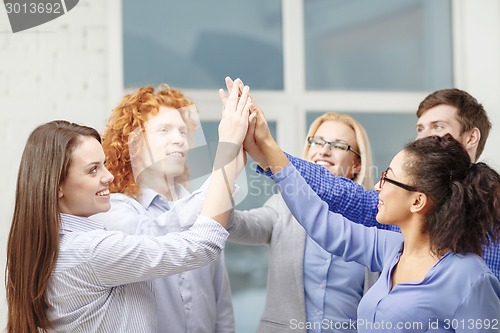 Image of creative team doing high five gesture in office