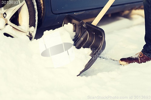 Image of closeup of man digging up stuck in snow car