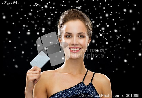 Image of smiling woman in evening dress holding credit card