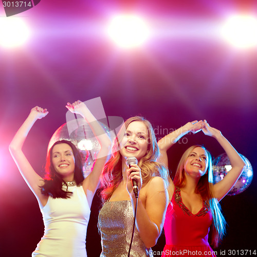 Image of three smiling women dancing and singing karaoke