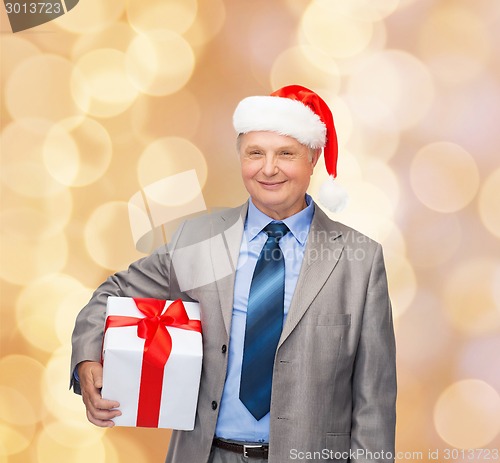 Image of smiling man in suit and santa helper hat with gift