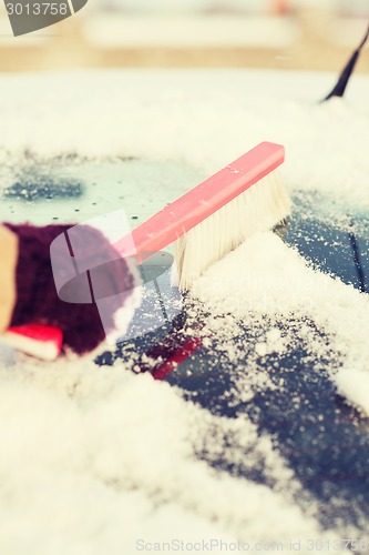 Image of woman cleaning snow from car back window