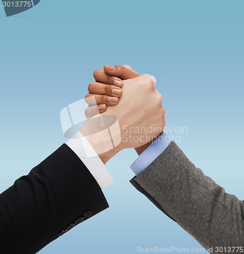 Image of close up of two hands multiracial armwrestling