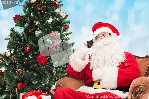 Image of santa claus with smartphone and christmas tree