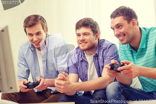 Image of smiling friends playing video games at home