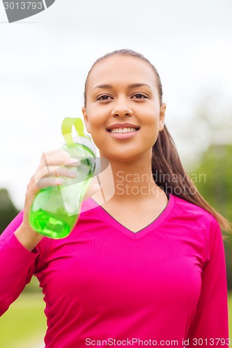Image of smiling woman drinking from bottle