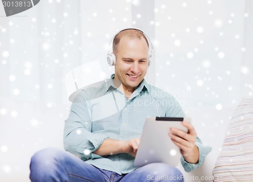 Image of smiling man with tablet pc sitting on couch