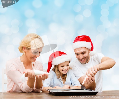 Image of happy family in santa helper hats cooking