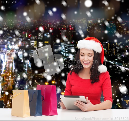 Image of smiling woman with shopping bags and tablet pc