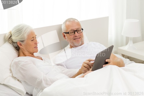 Image of happy senior couple with tablet pc at home