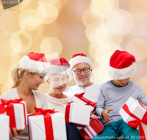 Image of happy family in santa helper hats with gift boxes