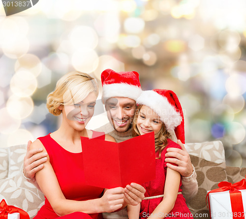 Image of happy family in santa hats with greeting card
