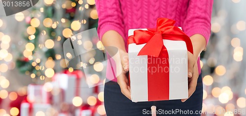 Image of close up of woman in pink sweater holding gift box