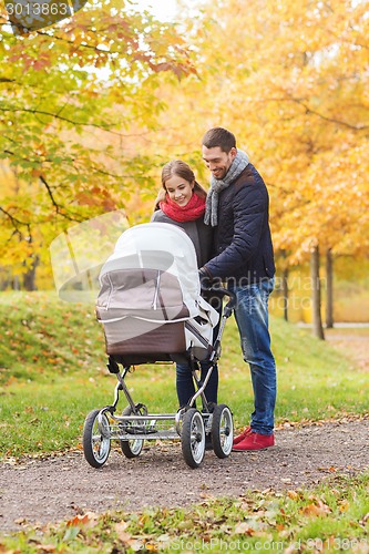 Image of smiling couple with baby pram in autumn park