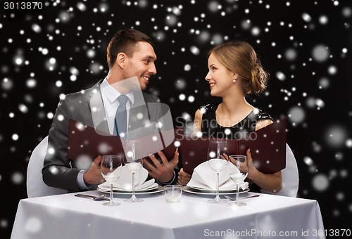 Image of smiling couple with menus at restaurant