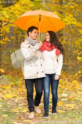 Image of smiling couple with umbrella in autumn park