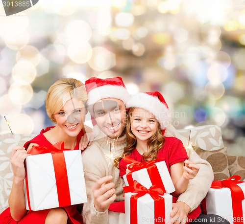 Image of happy family in santa helper hats with gift boxes