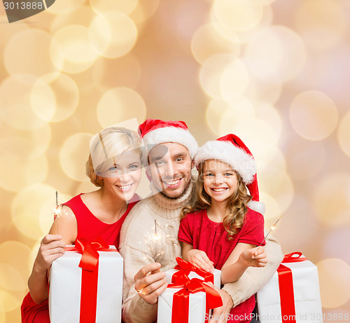 Image of happy family in santa helper hats with gift boxes