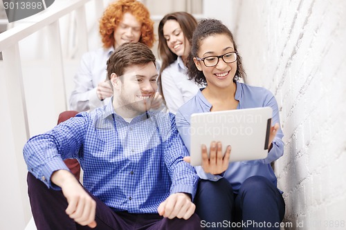 Image of team with tablet pc computer sitting on staircase