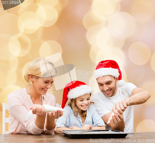 Image of happy family in santa helper hats cooking