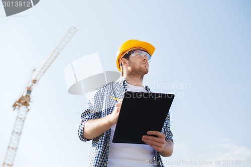 Image of builder in hardhat with clipboard outdoors