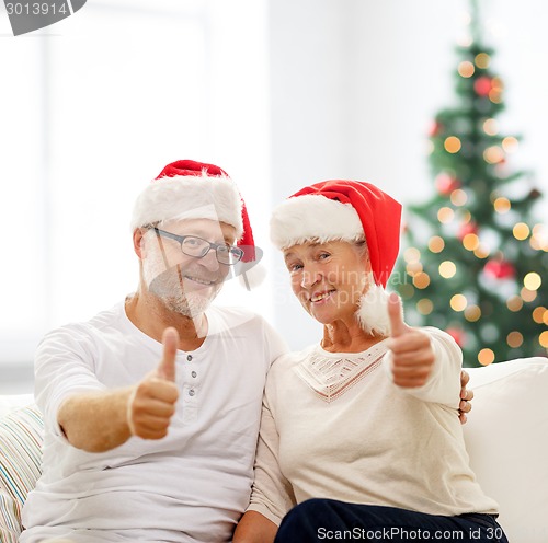Image of happy senior couple in santa helper hats