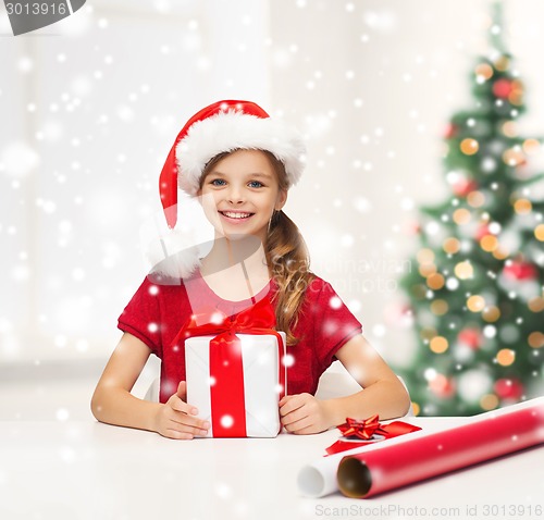 Image of smiling girl in santa helper hat with gift box