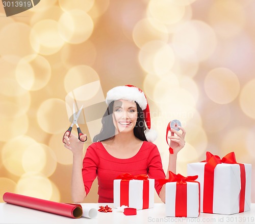 Image of smiling woman in santa helper hat packing gifts