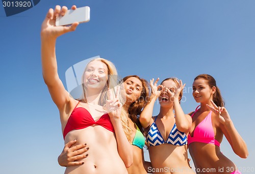 Image of group of smiling women making selfie on beach