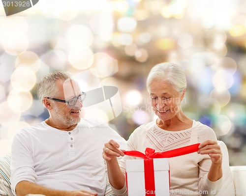 Image of happy senior couple with gift box at home