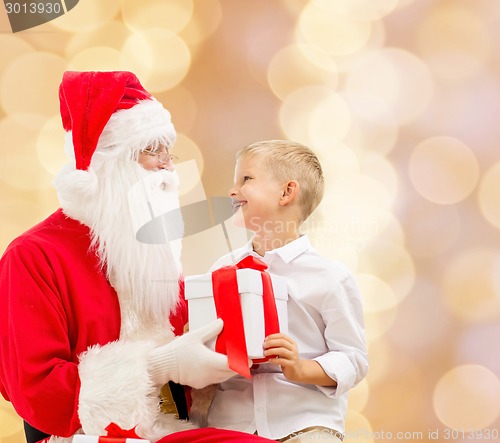 Image of smiling little boy with santa claus and gifts