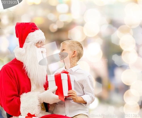 Image of smiling little boy with santa claus and gifts