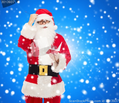 Image of man in costume of santa claus with notepad