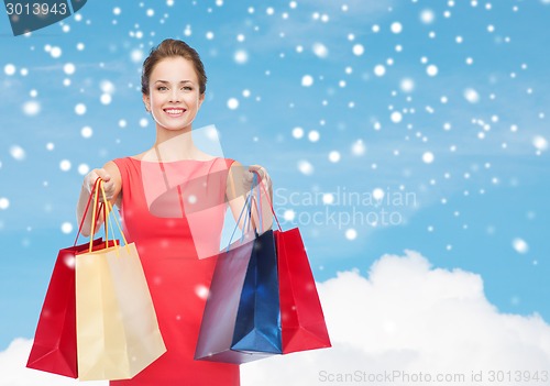 Image of smiling elegant woman in dress with shopping bags
